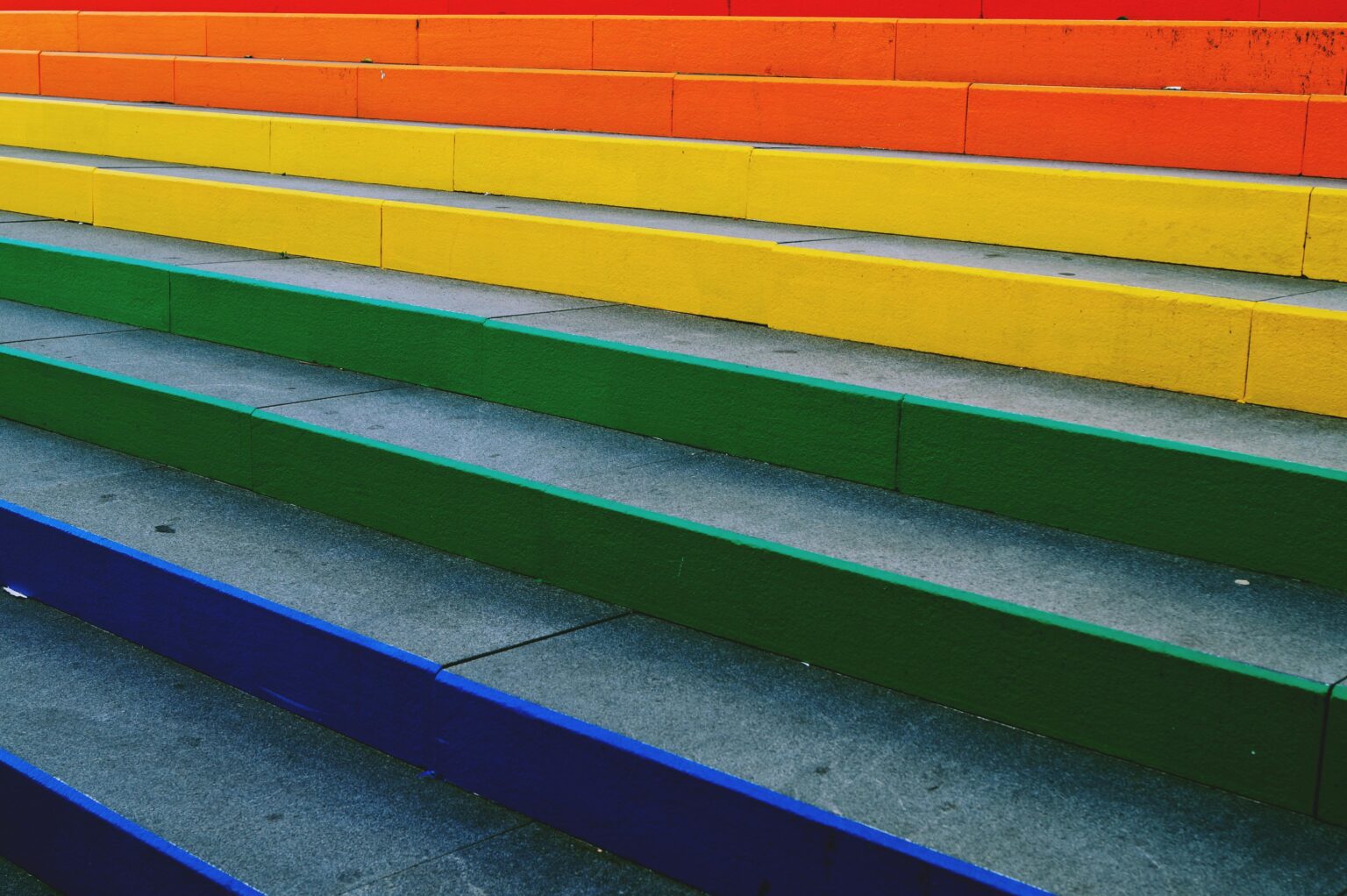 Vibrant rainbow-colored steps create a striking urban art display, perfect for background and design inspiration.